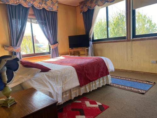 una camera con letto, TV e finestre di Hostal Buenaventura a Valdivia