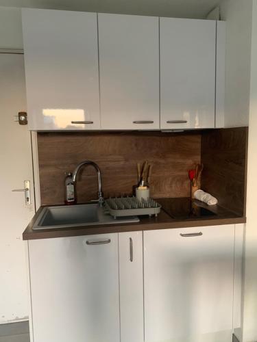 a kitchen with white cabinets and a sink at App T2 climatisé , plage 200 m in Sète