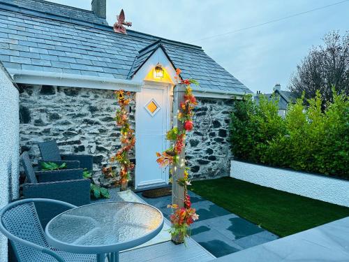 a garden with a table and a white door with a light at White Mermaid Cottage Anglesey Holidays in Newborough