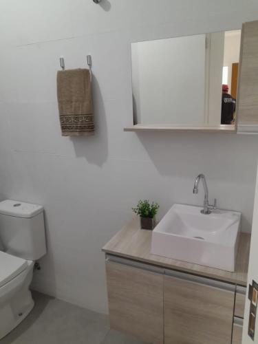 La salle de bains blanche est pourvue d'un lavabo et de toilettes. dans l'établissement Sobrado Itajuba, à Barra Velha