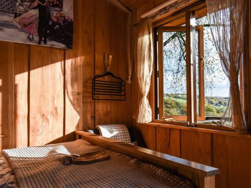 a bedroom with a bed in a wooden room with a window at Wampford Woodland Retreat - Kings Cabin in George Nympton
