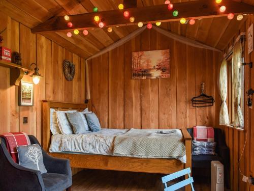 a bedroom with a bed in a wooden room at Wampford Woodland Retreat - George Cabin in George Nympton