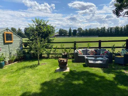 a couch sitting in the grass in front of a fence at Beautiful shepherd’s hut in Newmarket