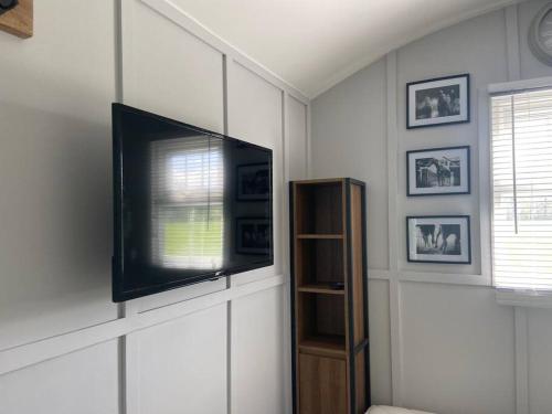 een woonkamer met een flatscreen-tv aan de muur bij Beautiful shepherd’s hut in Newmarket