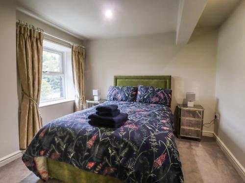a bedroom with a bed with a blanket and a window at 20 Wool Road in Oldham