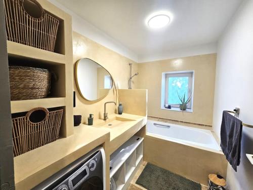 ein Badezimmer mit einem Waschbecken, einer Badewanne und einem Spiegel in der Unterkunft Le gîte de la marquise - Elégant appartement avec terrasse - in Montboucher-sur-Jabron