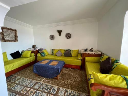 a living room with yellow couches and a table at Maison Berj in Oualidia