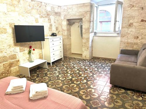 - un salon avec un canapé et une télévision dans l'établissement Antiche Mura Apartments"Bianco di Puglia" cucina 1 camera da letto più divano letto, à Turi