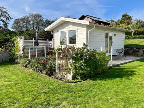 a small white house with a fence in a yard at Gästhus vid hav och strand in Åsa