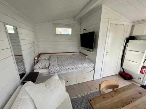 a small bedroom with a bed and a tv at Gästhus vid hav och strand in Åsa