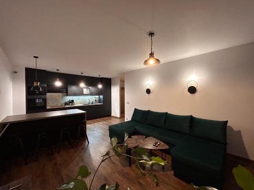 a living room with a green couch and a kitchen at BoleslaviaApartments - Apartament Arte 2 - parking free, EV in Bolesławiec