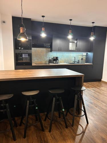 a kitchen with a bar with four stools in it at BoleslaviaApartments - Apartament Arte 2 - parking free, EV in Bolesławiec