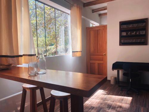 uma sala de jantar com uma mesa de madeira e uma janela em La Casa de Damien em Urubamba