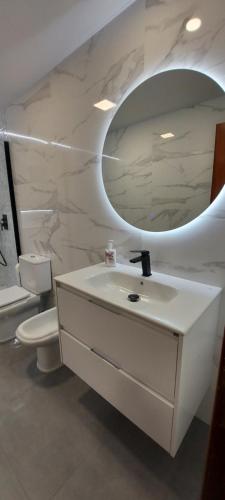 Baño blanco con lavabo y espejo en Apartamento Xanela o Mar en Laxe