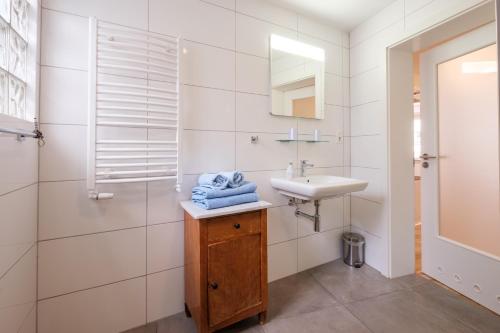 Baño blanco con lavabo y espejo en Alte Buchbinderei Apartments, en Baden-Baden