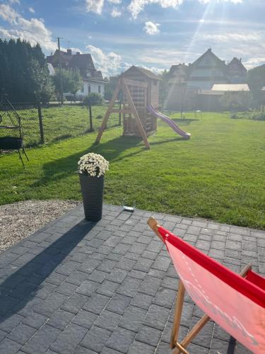 a red chair sitting on a patio with a playground at Apartamenty u Petuski in Szaflary