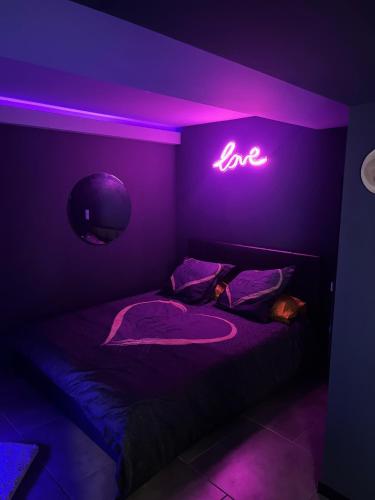 - une chambre avec un lit doté d'un signe d'amour néon dans l'établissement Chill & Love Bergerac, à Bergerac