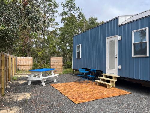 a blue tiny house with a picnic table and benches at The Abb Tiny Home in Perry