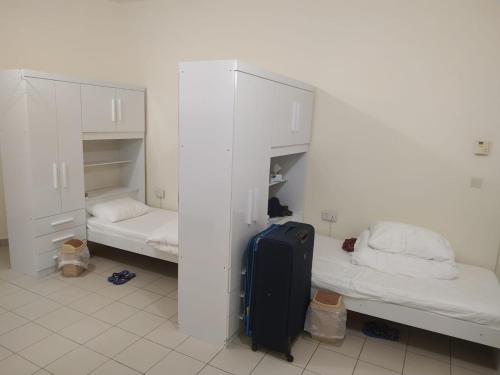a room with two beds and a suitcase in it at Ruby Star Hostel Dubai for Male- 4 R- 4 in Dubai