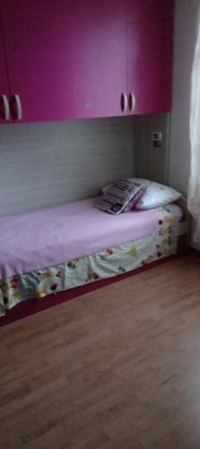 Ce lit se trouve dans un dortoir doté de murs violets et de parquet. dans l'établissement Appartamento Erika Lucca, à Lucques