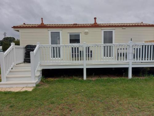 a house with a white porch and a white railing at Holiday Caravan in Clacton-on-Sea
