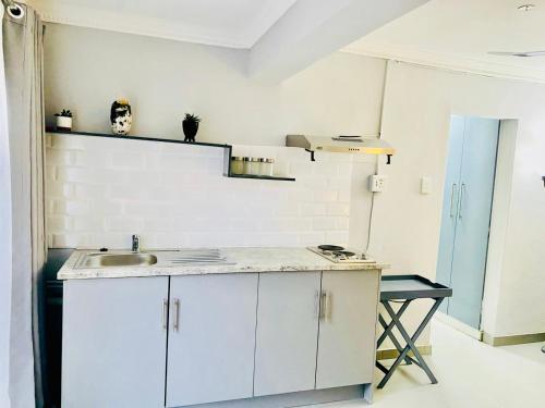 a kitchen with white cabinets and a sink at Pelican Corner in Durban