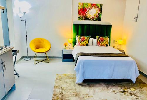 a bedroom with a bed with a green headboard and a yellow chair at Pelican Corner in Durban