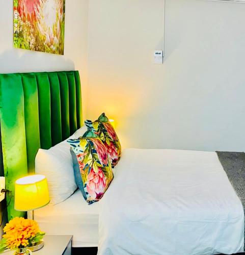 a bedroom with a white bed with a green headboard at Pelican Corner in Durban