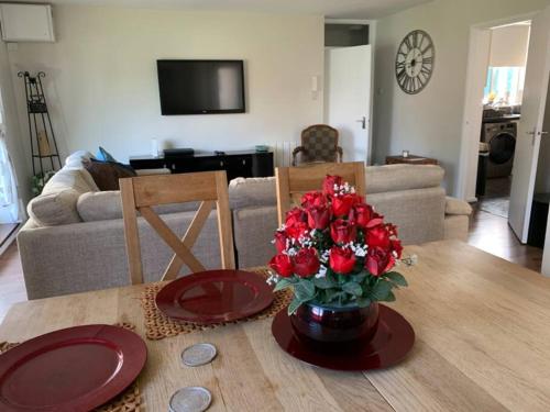 a table with a vase of red flowers on it at Spacious 2 Bed Elstree Borehamwood Hertfordshire in Elstree