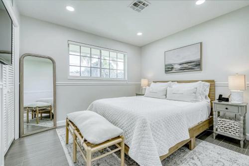 a white bedroom with a bed and a mirror at Avocado Hideaway in Boynton Beach