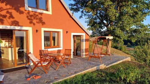 a patio with a table and chairs and a swing at Dadaj Park Home in Biskupiec