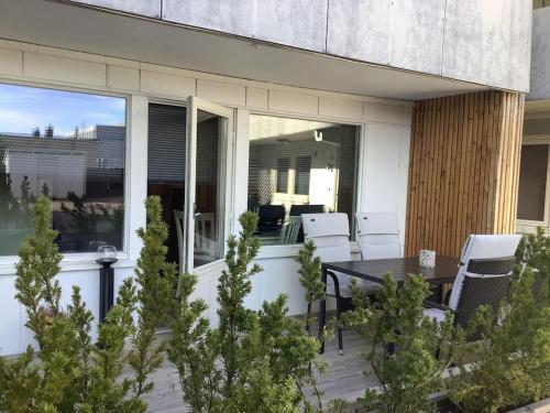 a patio with a wooden table and white chairs at SylviaBo in Skien