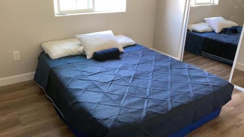 a bedroom with a bed with blue sheets and a mirror at We are in this together in Santa Ana