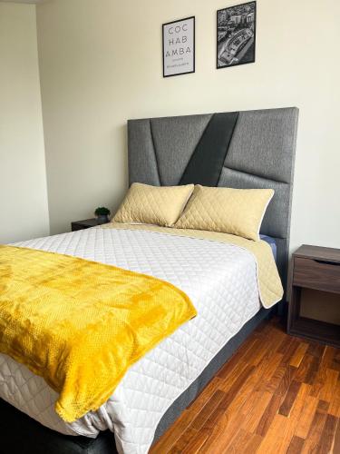 a bedroom with a bed with a yellow blanket on it at Hermoso Departamento completo en la mejor zona de Cochabamba in Cochabamba