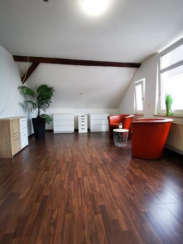 an empty room with a hard wood floor and red chairs at Schwert City Loft S42 in Verden