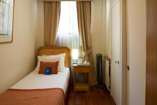 a small bedroom with a bed and a window at Hotel Presidente in Santiago