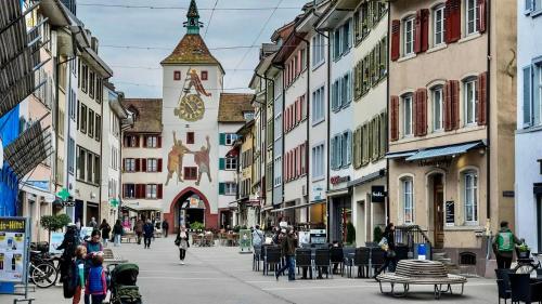 un grupo de personas caminando por una calle con una torre del reloj en Stedtli Liestal, en Liestal