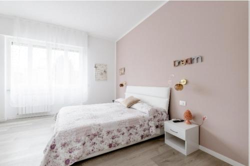 a white bedroom with a bed and a window at Casa di Kiki in Finale Ligure