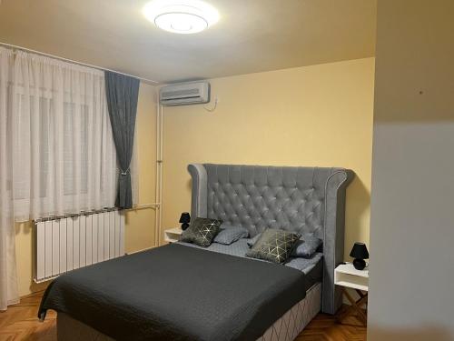 a bedroom with a bed with a gray headboard at Apartman 2E in Tuzla