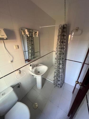 a white bathroom with a sink and a toilet at Hostal Sabor Fusion in La Pradera de Navalhorno