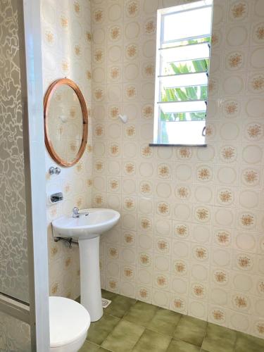 a bathroom with a sink and a toilet and a window at Pousada Natalli in Cabo Frio