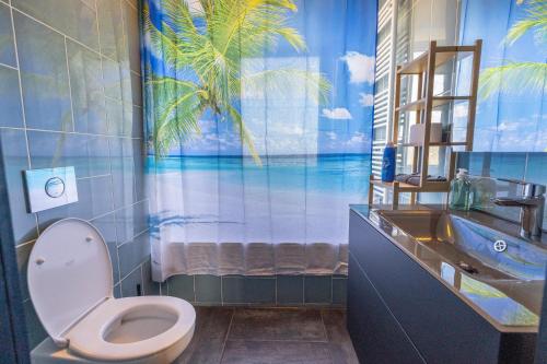 a bathroom with a toilet and a sink with a palm tree mural at Tram station rooms by CityPillow since 2019 in Hesperange