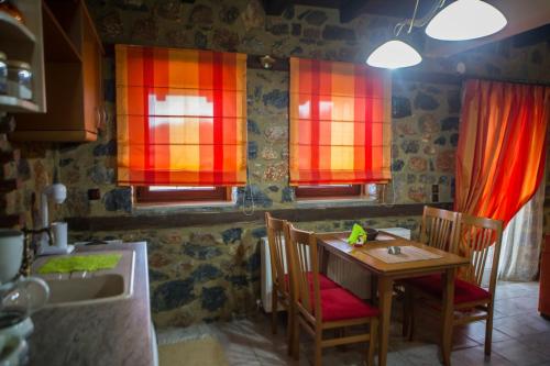 a kitchen with a table and chairs and red windows at Suites Mouses in Palaios Agios Athanasios