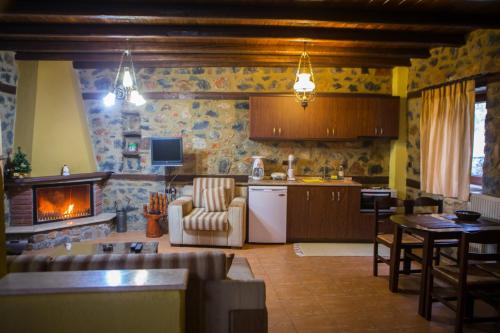 a kitchen with a living room with a fireplace at Suites Mouses in Palaios Agios Athanasios
