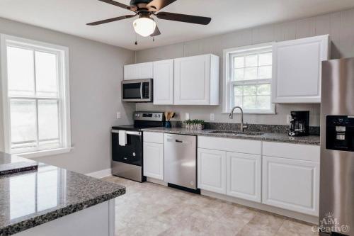 a kitchen with white cabinets and a ceiling fan at Near Waterfront, Maryland Renovated Home - Walk to Historic Downtown! in Cambridge