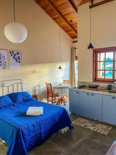 a bedroom with a blue bed and a table at Vila do Sol in Carrancas