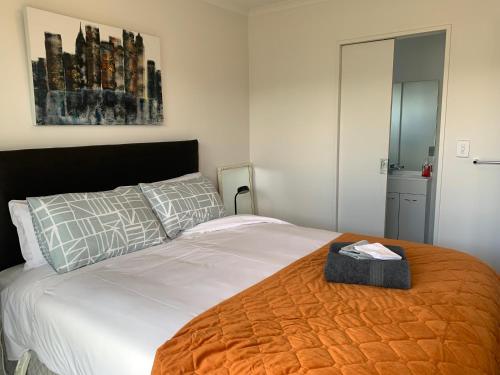 a bedroom with a bed with an orange blanket at A Beauty on Bligh St Te Anau in Te Anau
