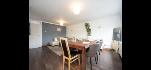 a dining room with a wooden table and chairs at Spacious Chessington home with parking & garden in Chessington
