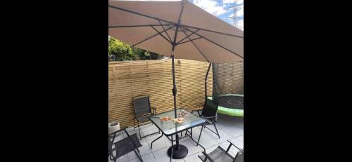 a patio with a table and an umbrella at Spacious Chessington home with parking & garden in Chessington