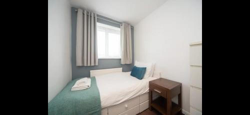 a small bedroom with a bed and a window at Spacious Chessington home with parking & garden in Chessington